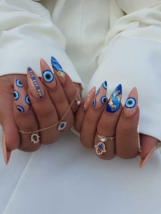 Vibrant Blue-Hued Almond Nails with Eye Motifs and Complementary Jewelry.