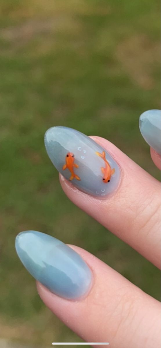 Elegant Blue Nail Design with Intricate Orange Goldfish Illustrations for a Playful Summer Look.