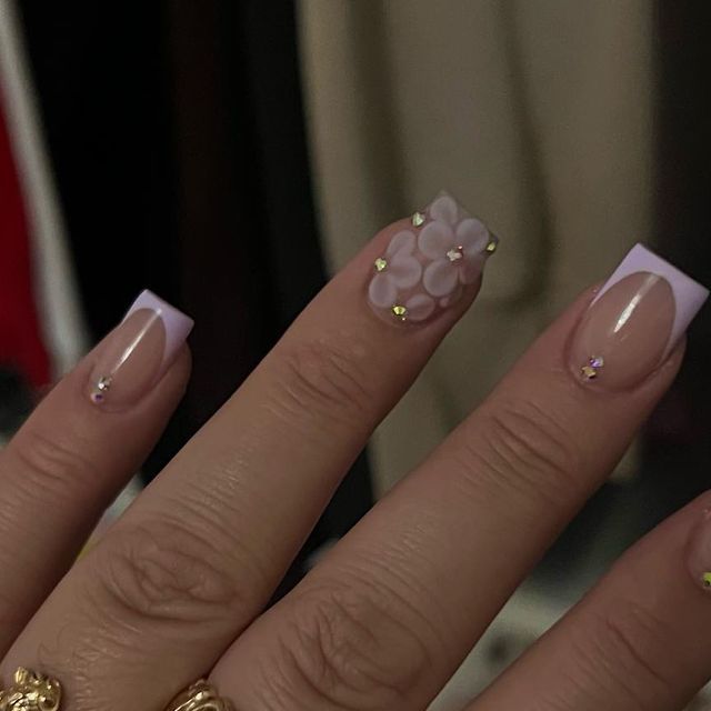 Sophisticated Lavender French Tip Nails with Floral Accents and Gemstone Embellishments.