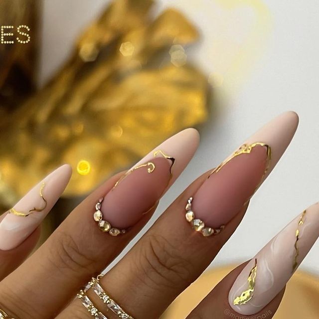 Elegant Stiletto Nails: A Glamorous Blend of Soft Nude, Glossy White, and Gold Accents.