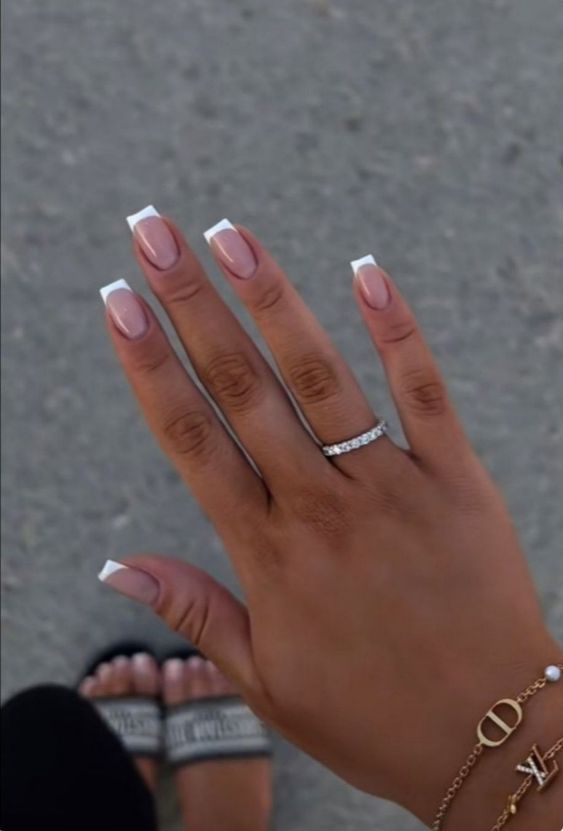 Elegant French Manicure with Soft Pink Base and Crisp White Tips, Enhanced by Subtle Jewelry.