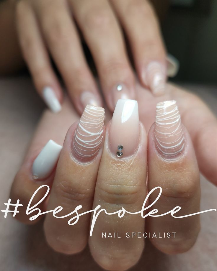 Chic Nail Art: Glossy White and Soft Pink with Intricate Patterns and Gemstone Accents.