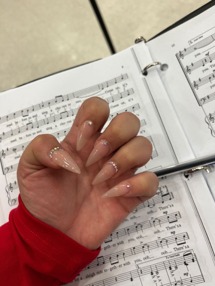 Chic Almond-Shaped Nails with Nude Polish and Subtle Rhinestone Accents.