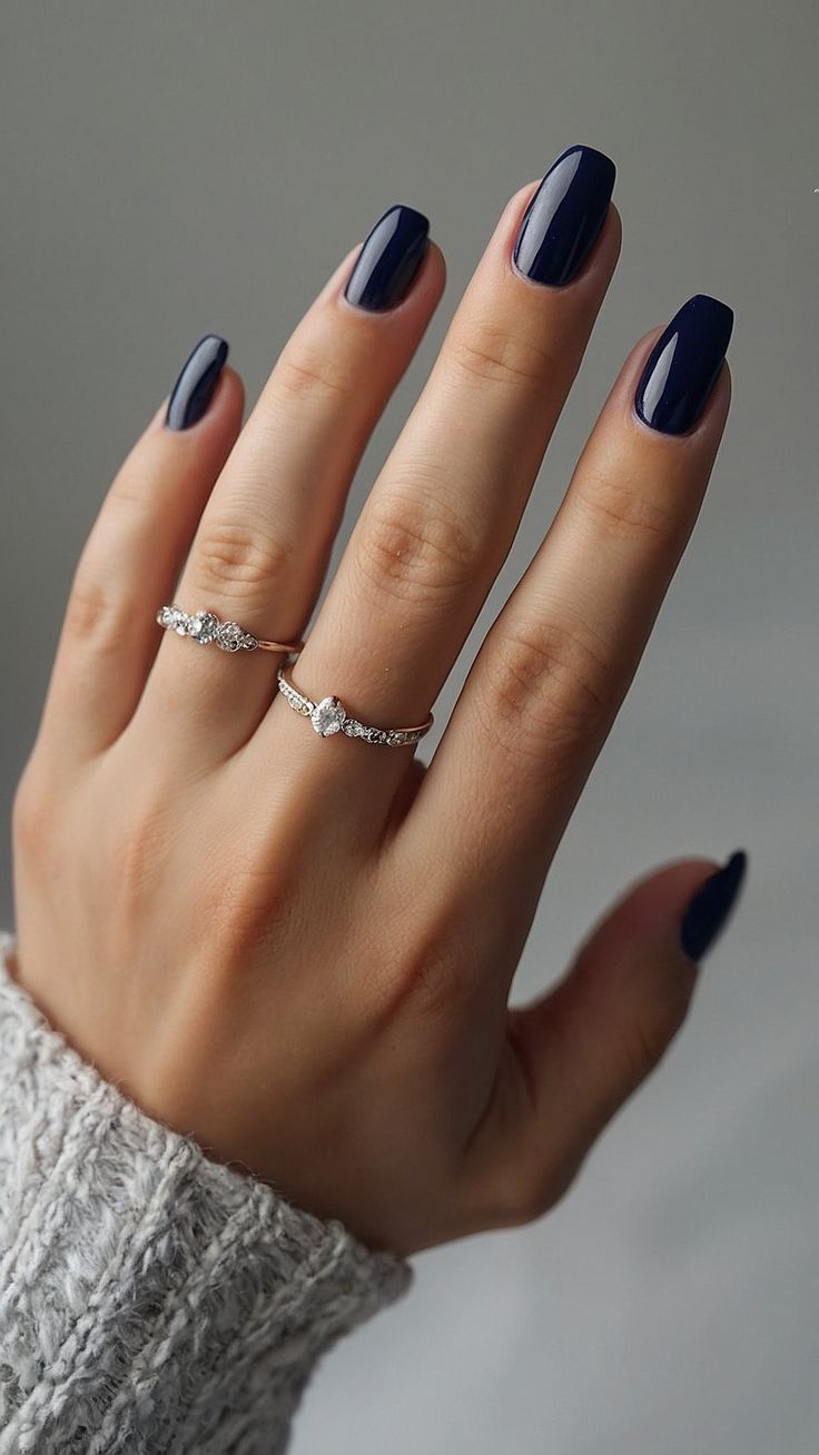 Sophisticated Dark Navy Nails with Glossy Finish and Delicate Silver Accessories for Versatile Elegance.