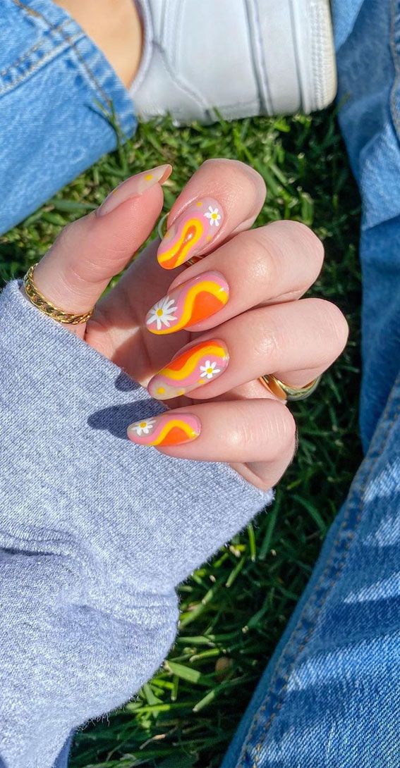 Playful Retro-Inspired Nail Design: Vibrant Orange and Yellow Swirls with Whimsical White Daisies.