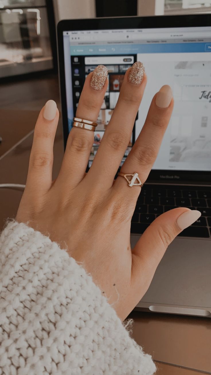 Chic Matte and Glitter Nail Design with Sparkling Accent and Minimalist Rings.