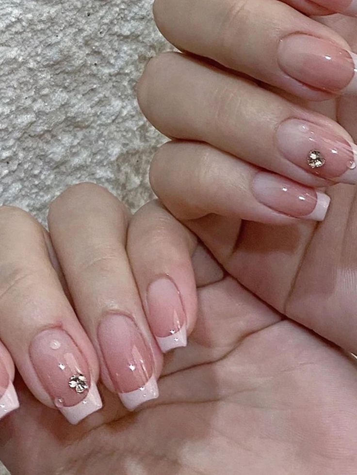 Sophisticated Nail Art: Soft Nude Base with Classic French Tips and Sparkling Embellishments.