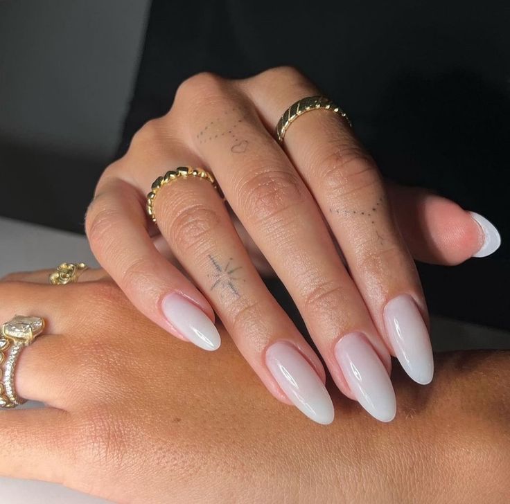 Sophisticated Almond-Shaped Ombre Nails with Delicate Pink-to-White Gradient and Gold Accents.