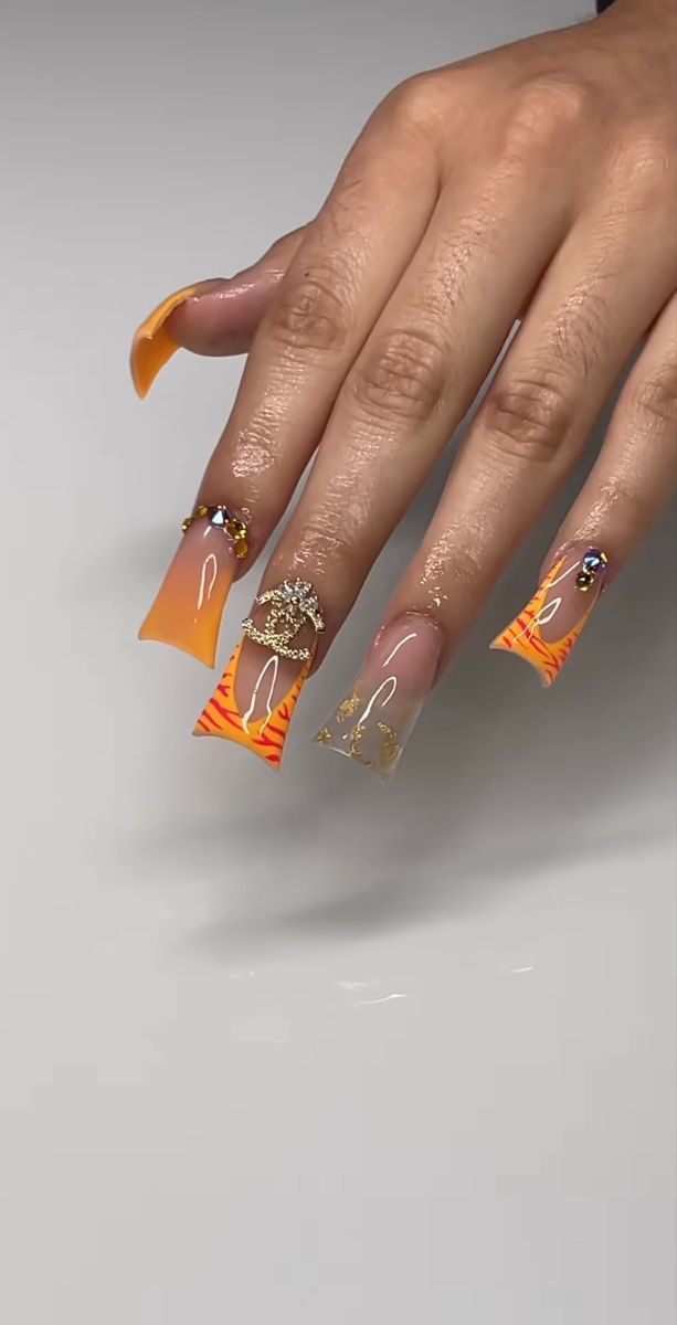 Bold and Playful Orange Gradient Nail Design with Intricate Details and Glossy Finishes.