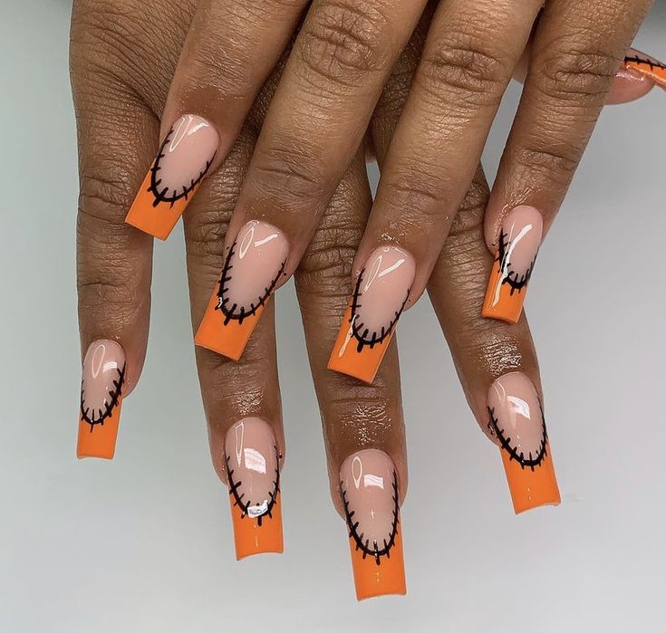 Whimsical Orange-Tipped Nail Design: A Playful Blend of Nude, Glossy Finish, and Spooky Stitching.