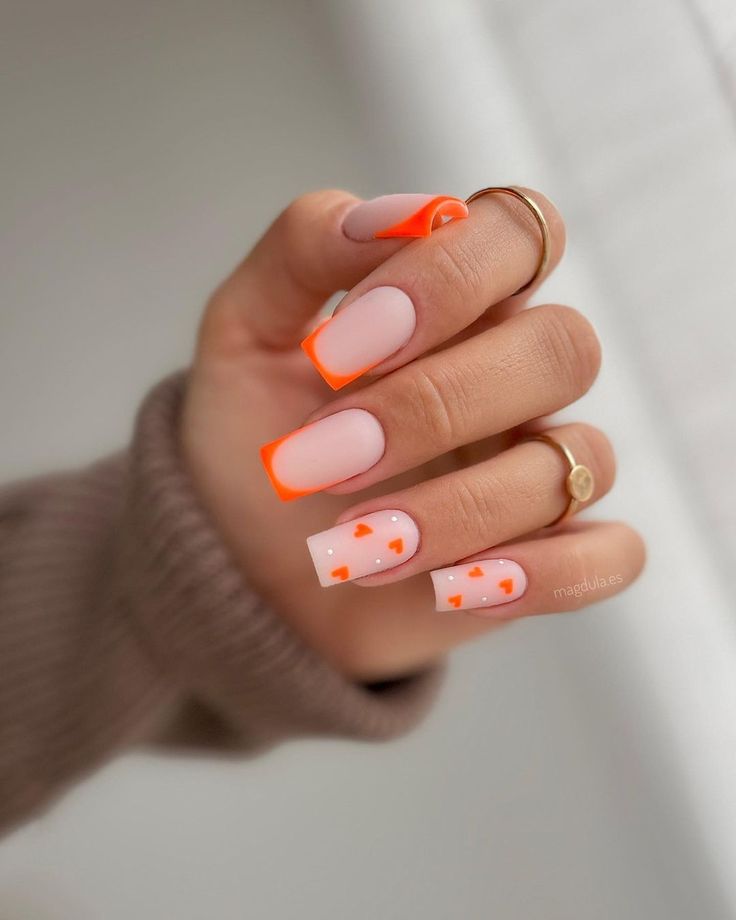 Chic Pastel Pink and Vibrant Neon Orange Nail Design with Bold Tips and Heart Accents.