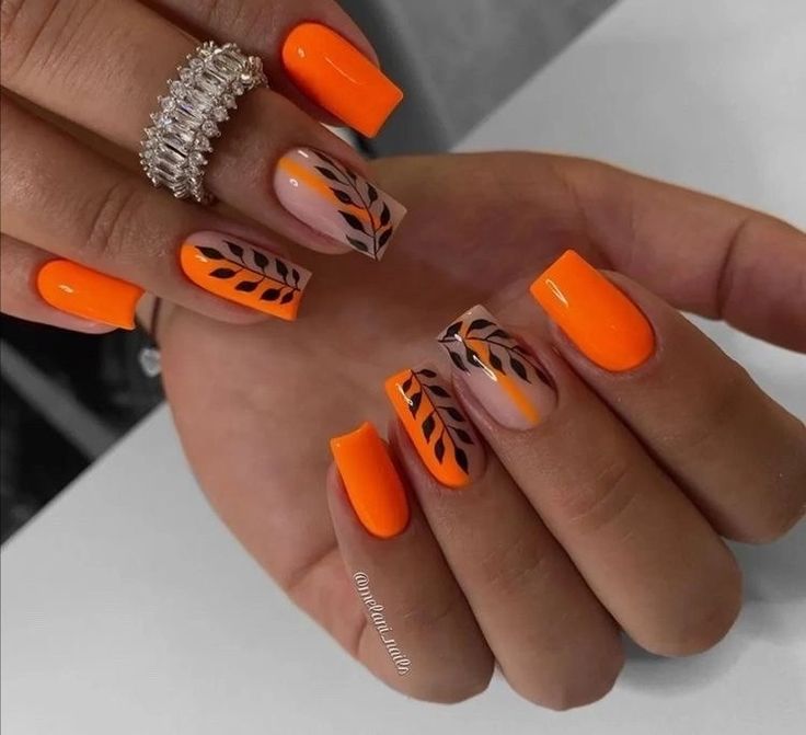 Chic Vibrant Orange Nail Design with Elegant Black Leaf Patterns and a Statement Ring.