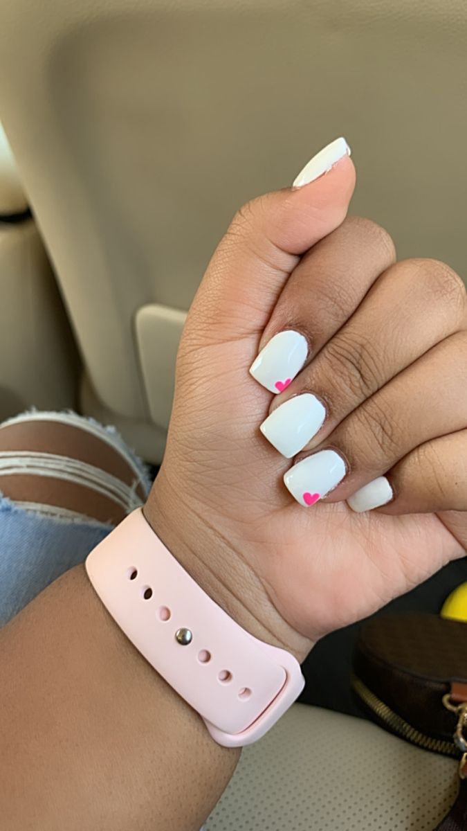 Elegant Chic White Nails with Playful Pink Heart Designs and Matching Soft Pink Wristband