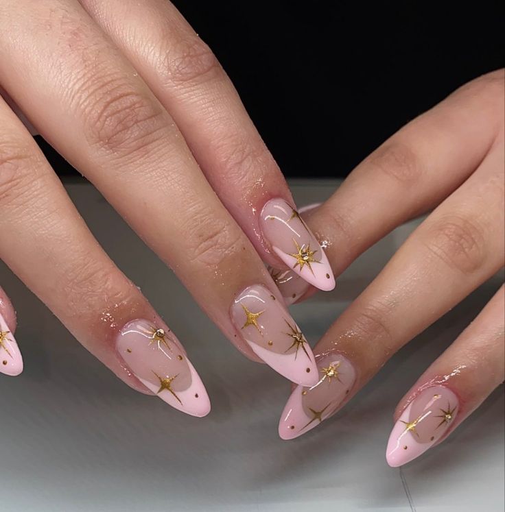 Sophisticated Soft Pink Nail Design with Glossy Finish and Intricate Gold Star Accents.