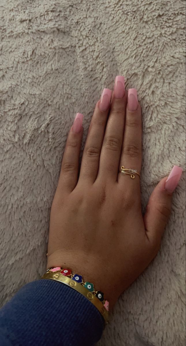 Chic Elegance: Polished Pink Acrylic Nails and Complementary Jewelry in a Cozy Setting.