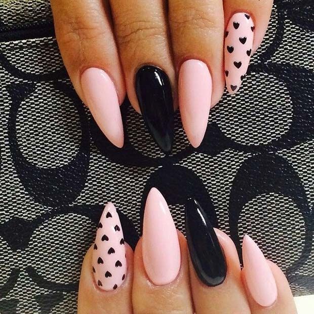 Chic Almond-Shaped Nail Design: Soft Pink and Sleek Black with Heart Patterns.