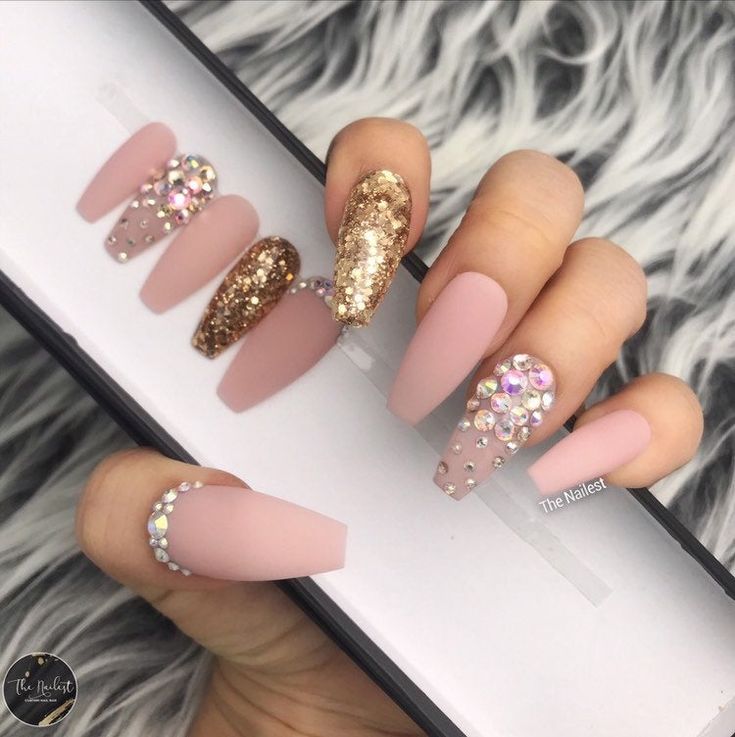 Sophisticated Matte Pink and Shimmering Gold Nail Design with Rhinestone Accents.