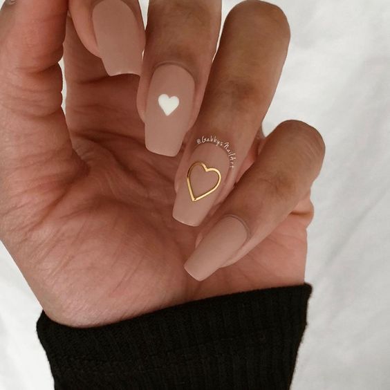 Chic Minimalist Nude Nail Design with Heart Motifs in Gold and White.