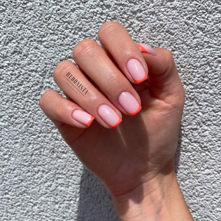 Vibrant Orange-Tipped Soft Pink Nail Design: A Chic Pop of Color for Any Occasion.