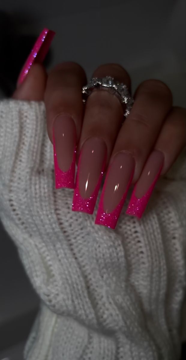 Vibrant Ombre Nail Design: Long Square Nails with Bold Neon Pink Glitter Tips on Soft Nude Base.