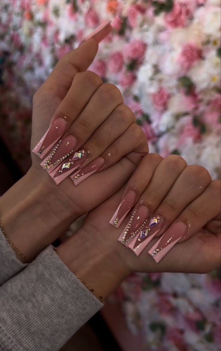 Luxurious Pink Acrylic Nail Design with Sparkling Gems and Gold Accents.