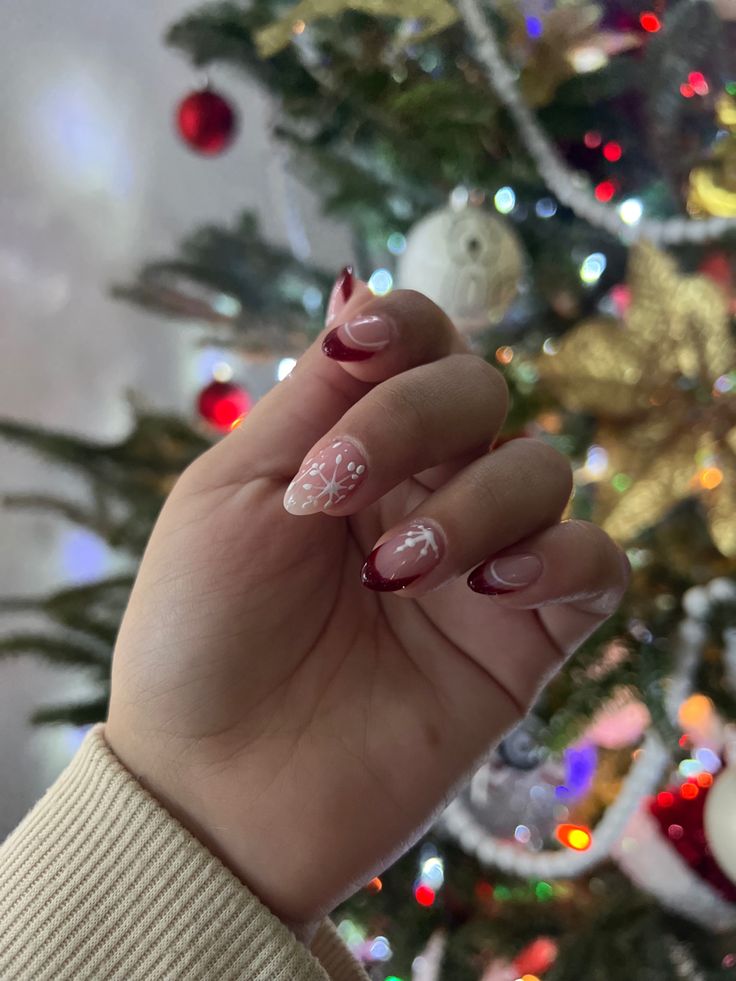 Sophisticated Holiday Nail Design: Deep Burgundy Tips with Nude Accents and Intricate Floral Patterns.