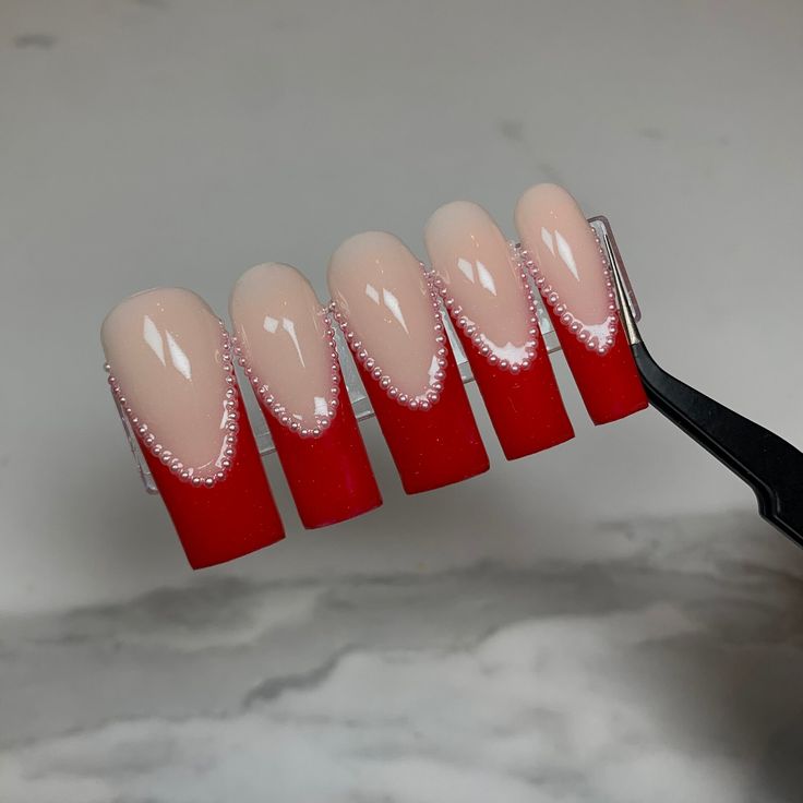 Chic Gradient Nail Design: Vibrant Red Tips Blending into Soft Nude with Elegant Pearl Accents.