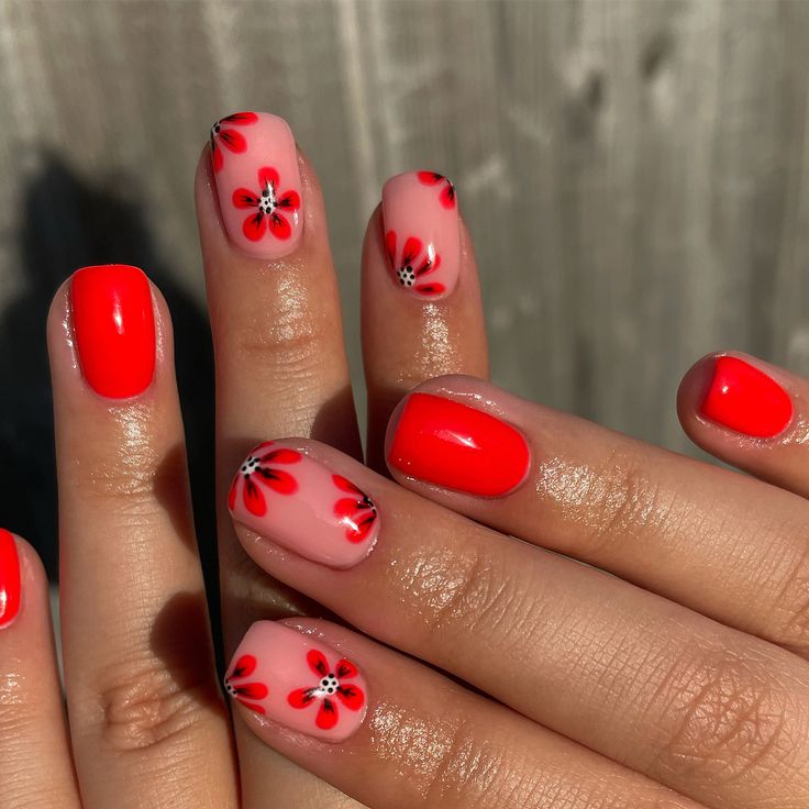 Vibrant Floral Nail Design: Glossy Red Flowers with Black Accents on Soft Pink Background.