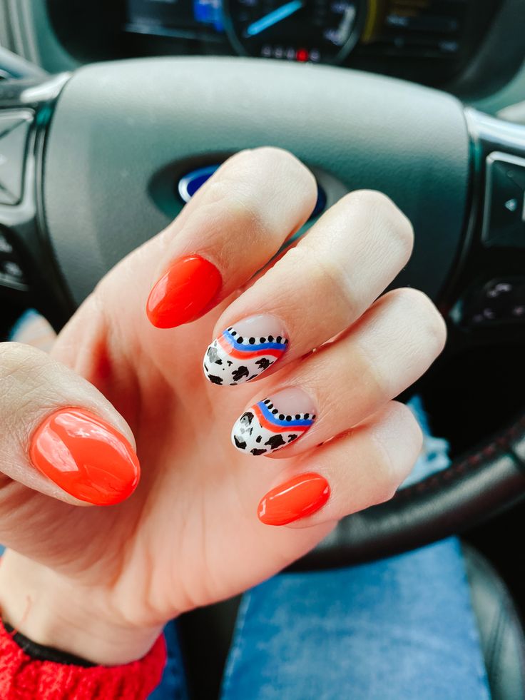 Chic Fiery Red Nail Design with Playful Cow Print and Blue Accents