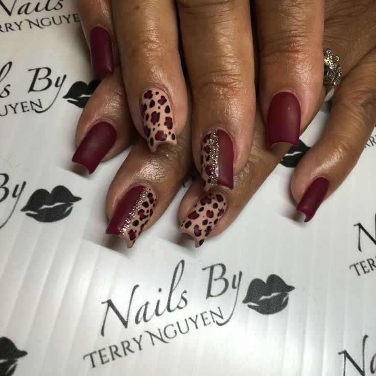 Fierce Deep Burgundy Nail Design with Playful Leopard Print and Glamorous Glitter Accents.