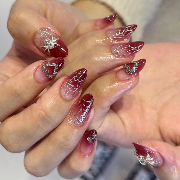 Striking Deep Burgundy Nail Design with Spider Web Patterns and Silver Accents.