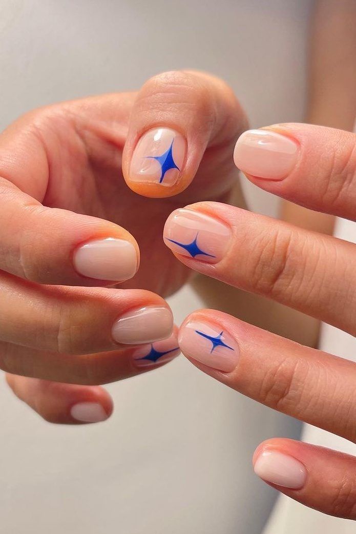 Chic Nude Nail Design with Playful Blue Starburst Accents.