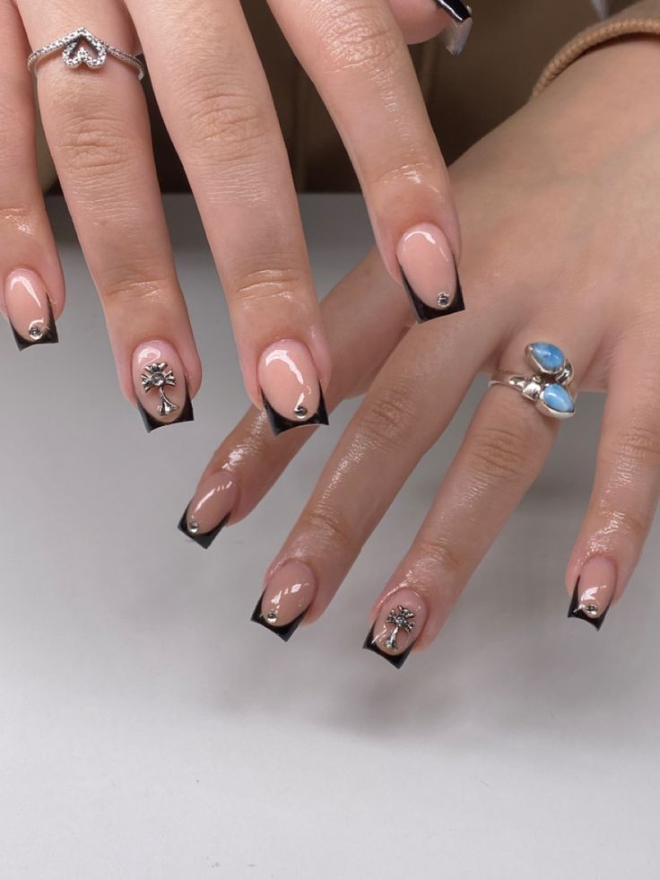 Sophisticated Nude and Bold Black Nail Design with Floral Embellishments for All Occasions.