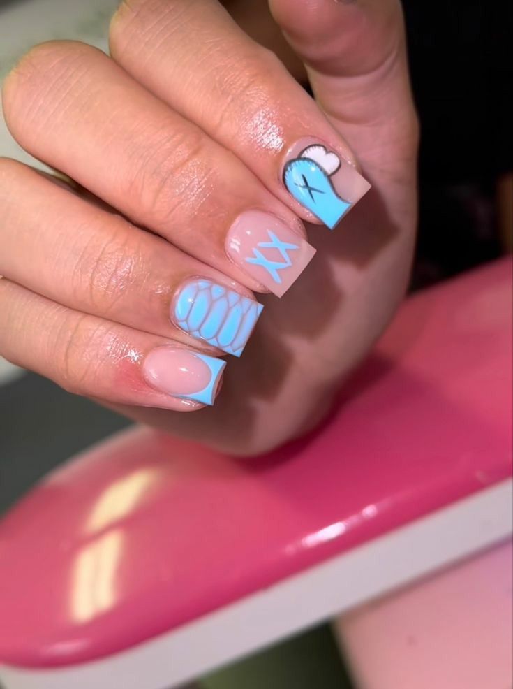 Creative Pastel Blue and Nude Nail Design with Unique Patterns and Playful Illustrations.