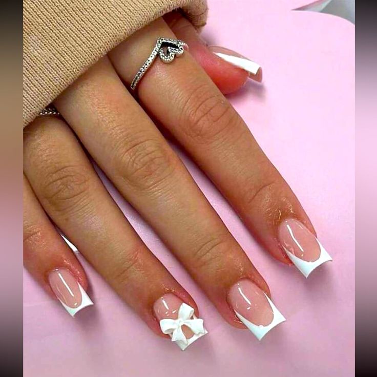 Chic French Manicure with Whimsical Bow Accent and Elegant Ring.