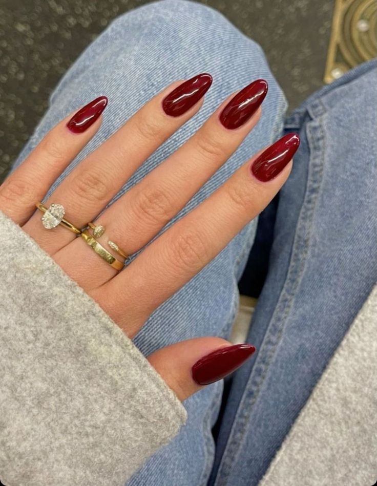 Elegant Burgundy Almond Nail Design with Sophisticated Gloss and Complementary Jewelry.