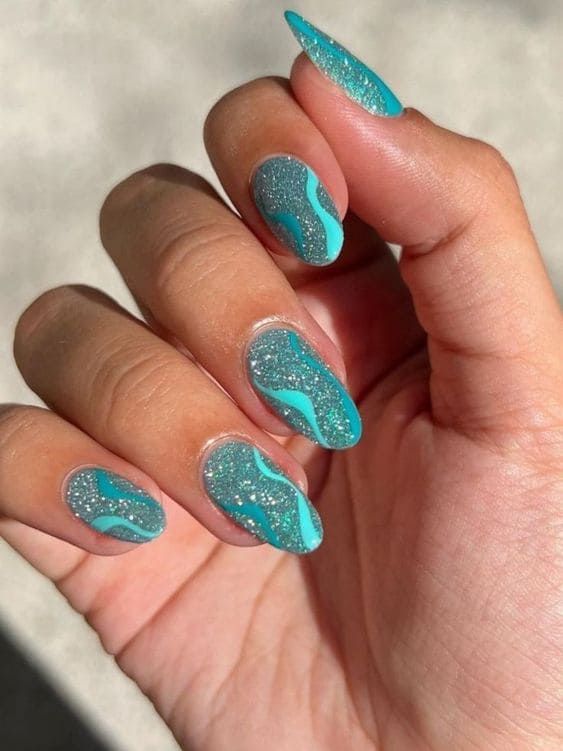 Vibrant Teal and Blue Abstract Nail Design with Glitter Accents.