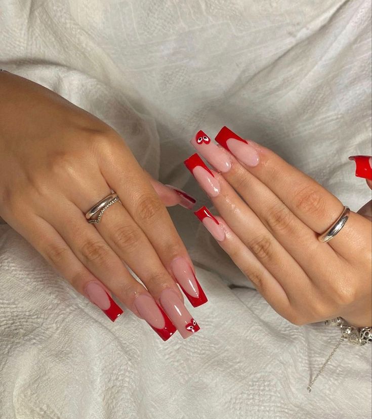 Bold Color Contrast Nail Design: Elegant Red Tips on Soft Pink Base with Unique Decorative Touch.