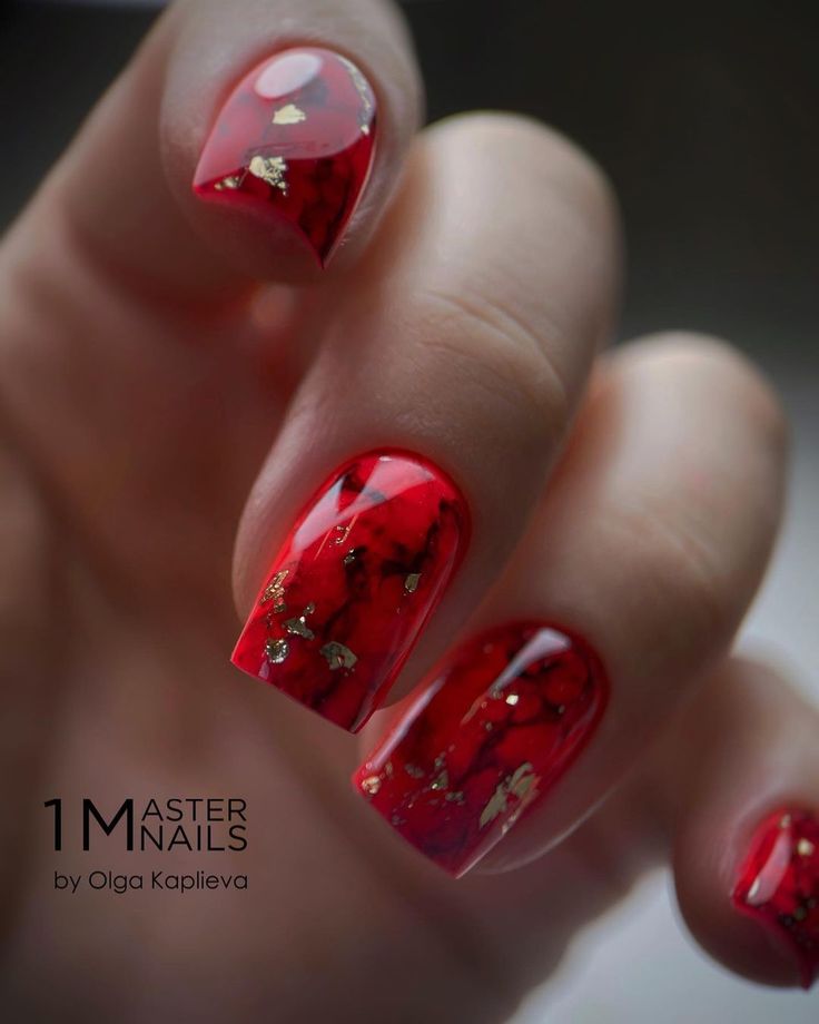 Bold Glossy Red Nail Design with Gold Flakes and Elegant Transparency.