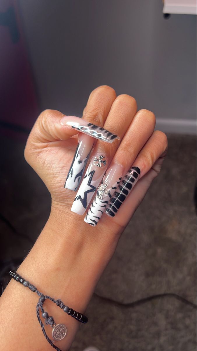 Bold Black and White Acrylic Nail Design with Abstract Patterns and Silver Accents.