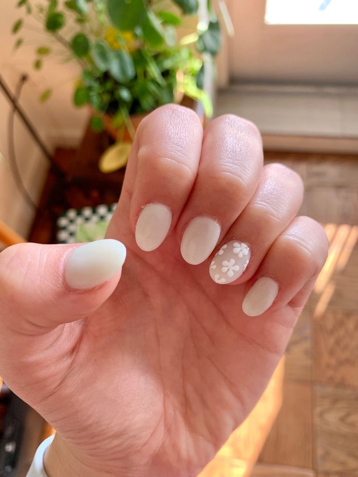 Chic White Nail Design with Playful Floral Accent for Any Occasion