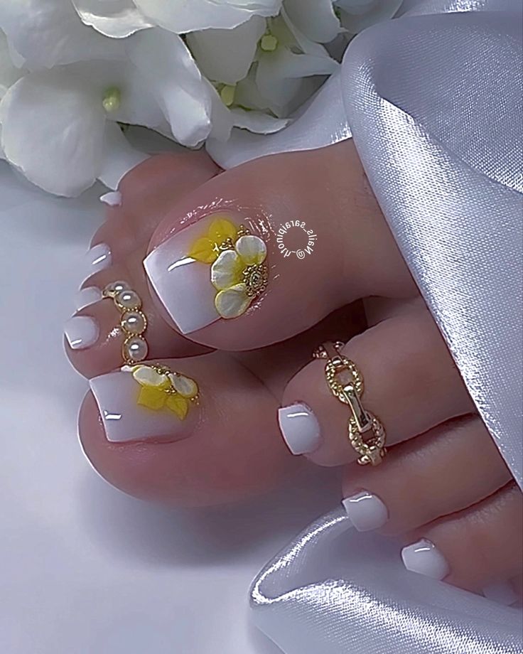 Chic White Nail Design with Floral Accents and Pearl-Gold Touches for a Whimsical Summer Look.