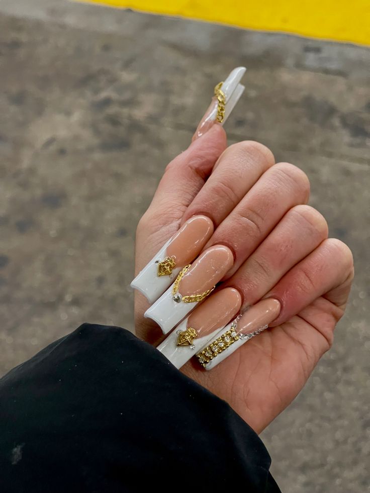 Sophisticated Long Square Nail Design with Nude and White Tones, Enhanced by Glamorous Gold Accessories and Luxurious Embellishments.