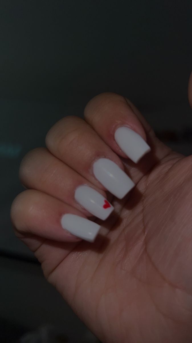 Chic White Nail Design with Playful Red Heart Accent for a Stylish Touch.