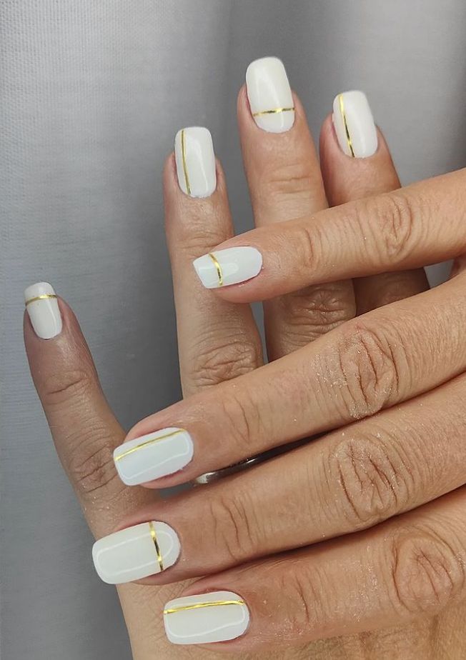 Sophisticated White Nail Design with Subtle Gold Stripes for Modern Minimalism and Glamour.