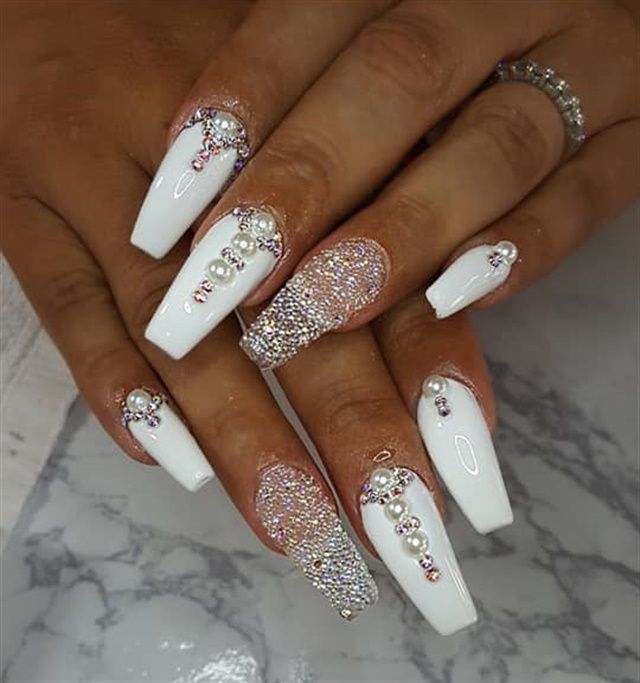 Glamorous White Nail Art with Rhinestones and Textured Designs for Special Occasions.