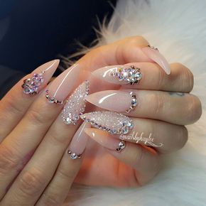 Sophisticated Nail Design: Glossy Nude Base with Glamorous Gems and Glitter.