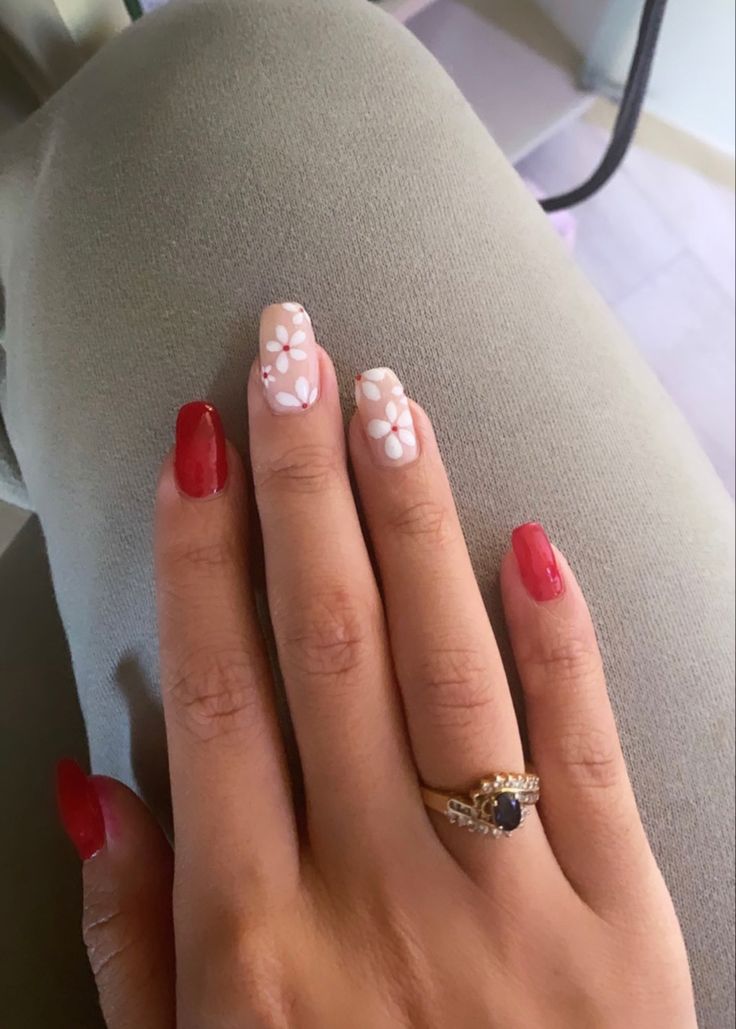 Vibrant Glossy Red and Soft Nude Nails with Charming Floral Accents.