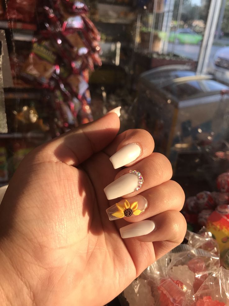 Chic Matte White Nails Accented with Vibrant Sunflower and Sparkling Gem Detailing.