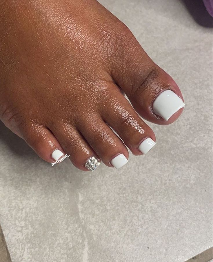 Chic Summer Pedicure: Crisp White Polish with Dazzling Rhinestone Accent for Elegant Sophistication.